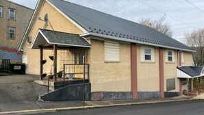 A single-story building with a gabled roof, a front porch, and a small attached garage.