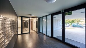 A modern hallway with a metal locker wall, a glass door leading outside, and a ceiling light.