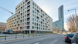 A modern multi-story building with a flat facade, large windows, and a parking lot.