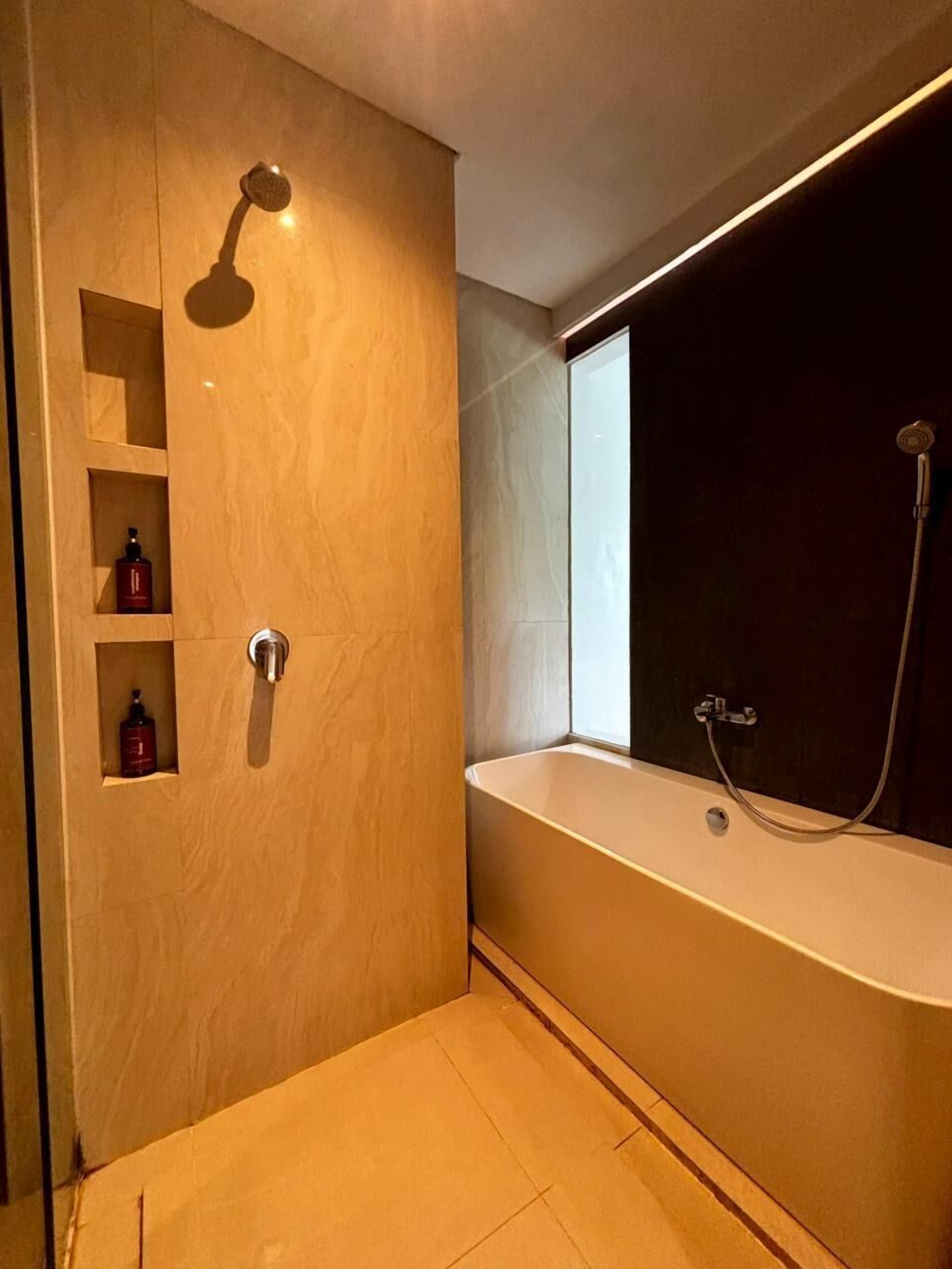 A modern bathroom with a walk-in shower, a bathtub, and built-in shelves with toiletries.