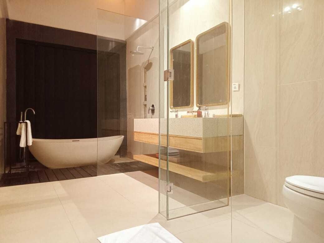 Ein modernes Badezimmer mit einer freistehenden Badewanne, einer in Glas eingefassten Duschkabine und einem WC.