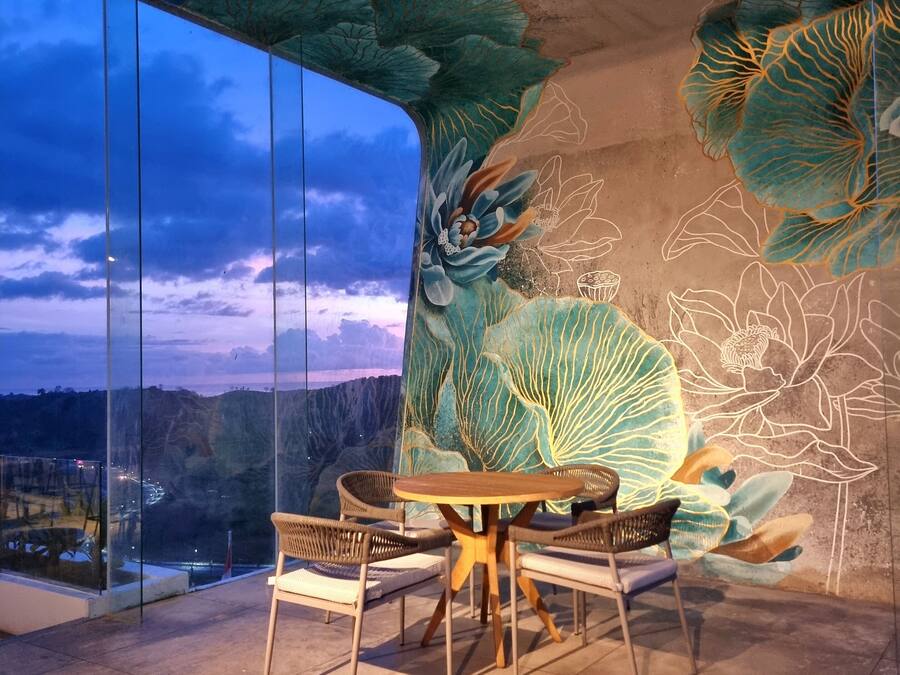 Uma área de jantar moderna com uma mesa redonda e quatro cadeiras, em frente a uma parede com um grande mural floral.
