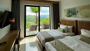 Une chambre d’hôtel moderne avec deux lits, un bureau et un balcon offrant une vue sur la verdure et les montagnes.