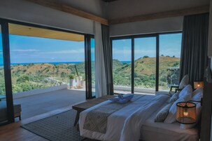 Un dormitorio con una cama grande, vistas al campo y un balcón.