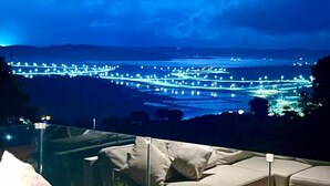 Un espace extérieur moderne aménagé avec des sièges, offrant une vue sur le paysage urbain illuminé la nuit.
