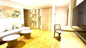 A modern living room with a sofa, two round tables, a TV, and a wooden floor.