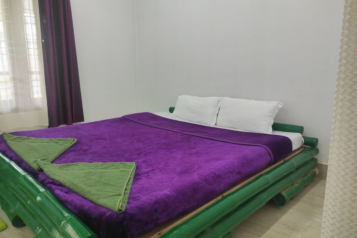A bed with a purple blanket and green pillows, a white headboard, and a green bed frame.