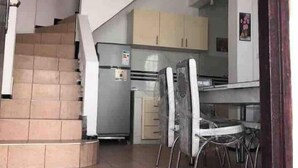 Una cocina con comedor, escalera y refrigerador.