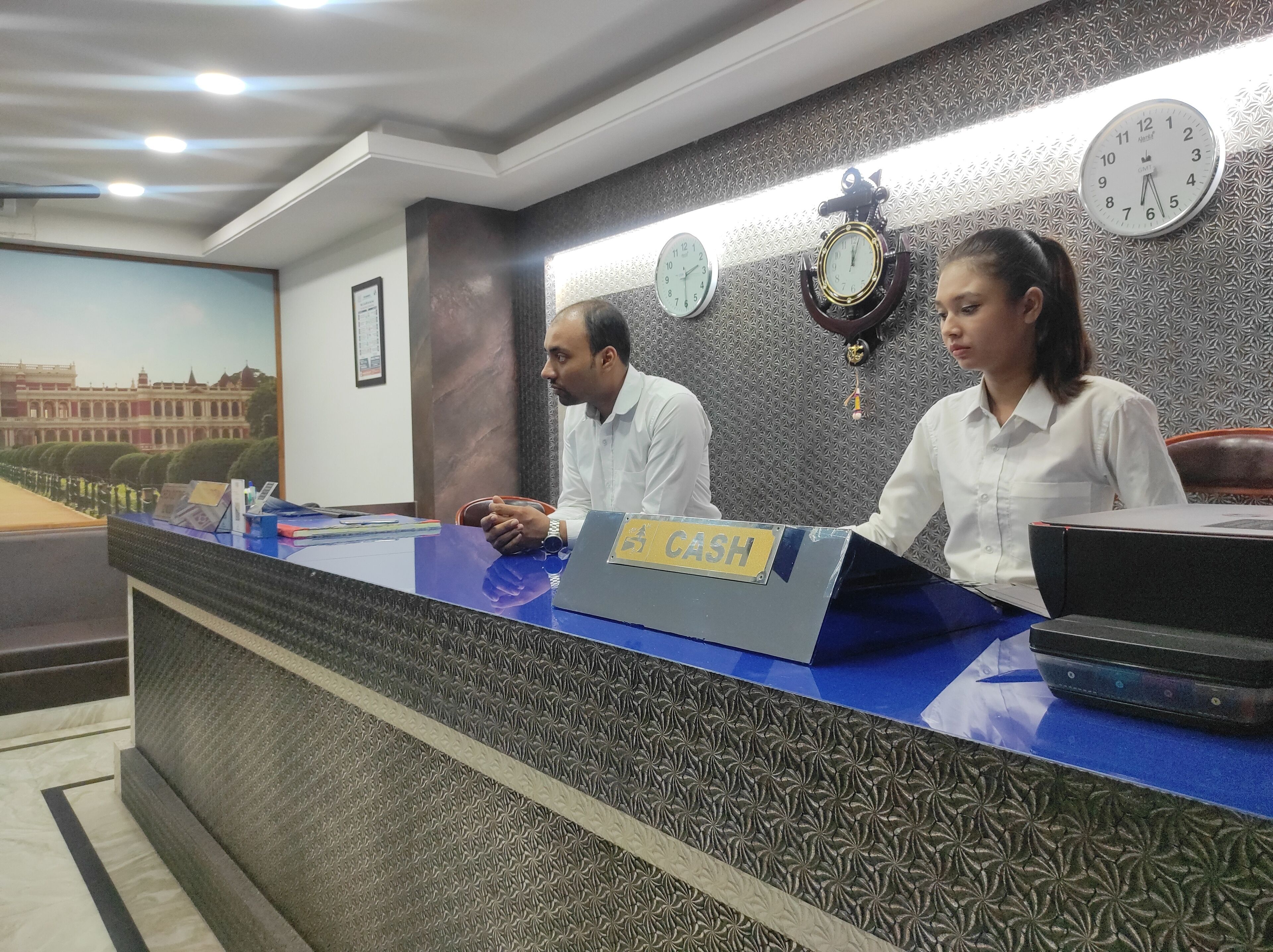A reception desk with a 'Cash' sign, multiple clocks, and a patterned wall.