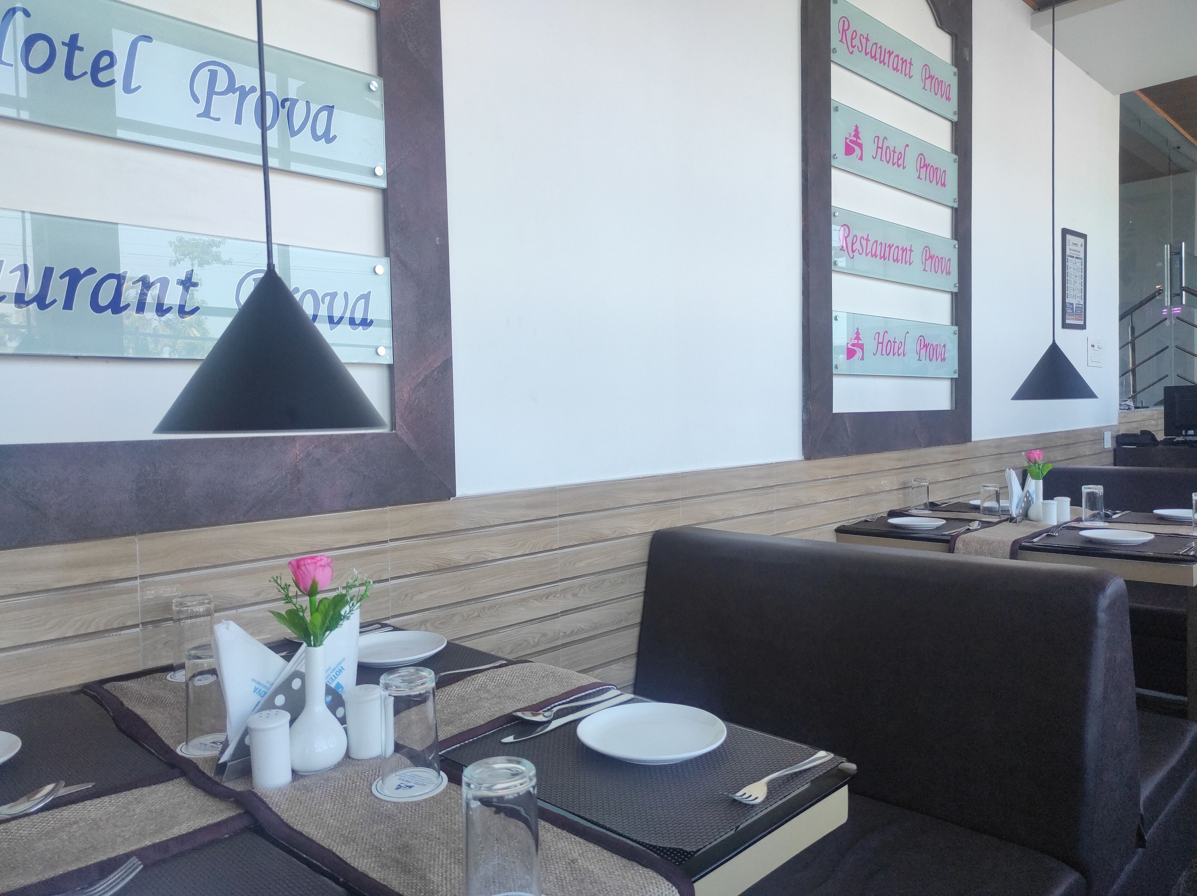 A restaurant with tables set for dining, a menu board, and a view of the hotel name.