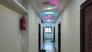 Um corredor com um extintor à esquerda, um cesto de lixo e uma porta à direita.