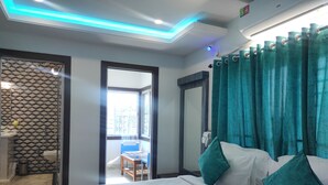 Quarto de hotel com uma cama, cortinas verde-água, uma janela e vista para o exterior.