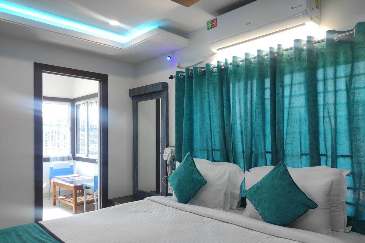 Ein Hotelzimmer mit Bett, Fön, Fenster mit Vorhängen und Blick nach draußen.