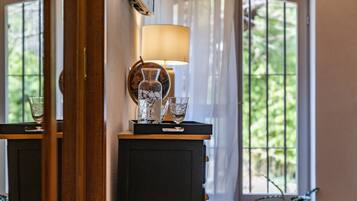 Una habitación con un escritorio de madera, una lámpara y dos vasos encima.