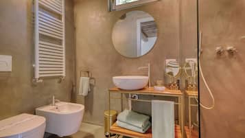 Een moderne badkamer met een witte badkuip, een witte wastafel en een houten opbergmeubel met een spiegel.