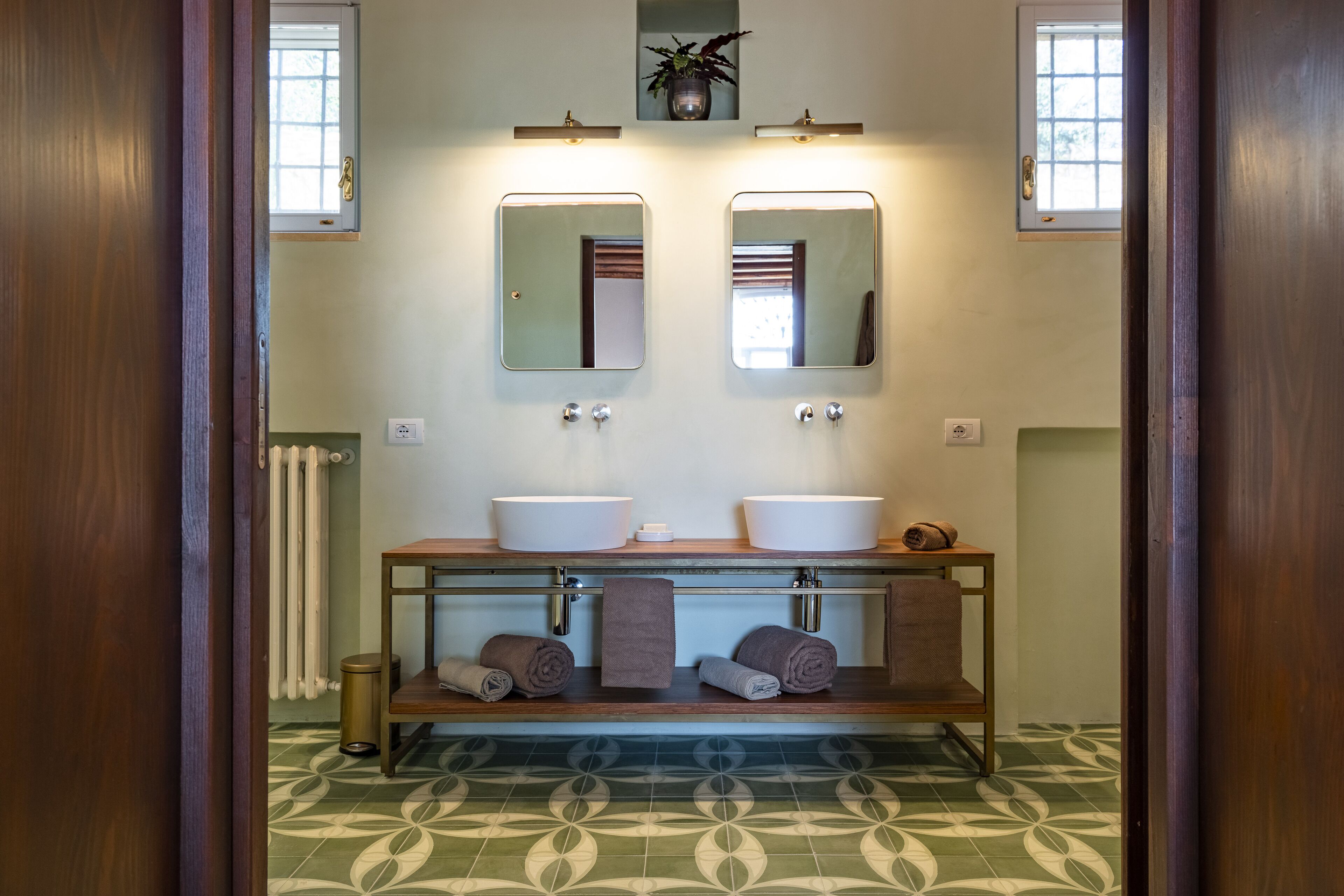 A bathroom with two sinks, a mirror, a towel rack, and a patterned floor.