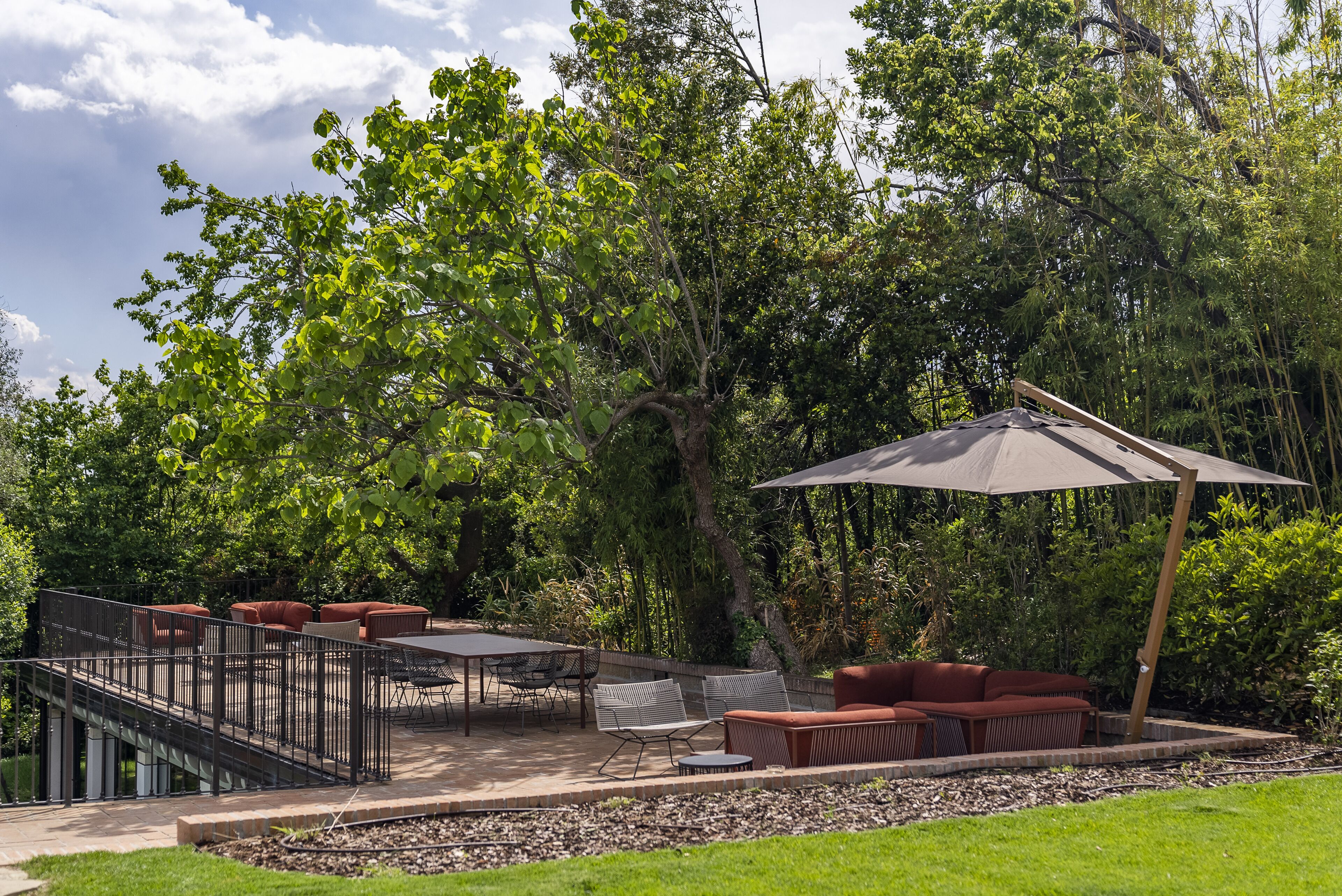 An outdoor patio with a table and chairs, a sofa, and a pergola with an umbrella.