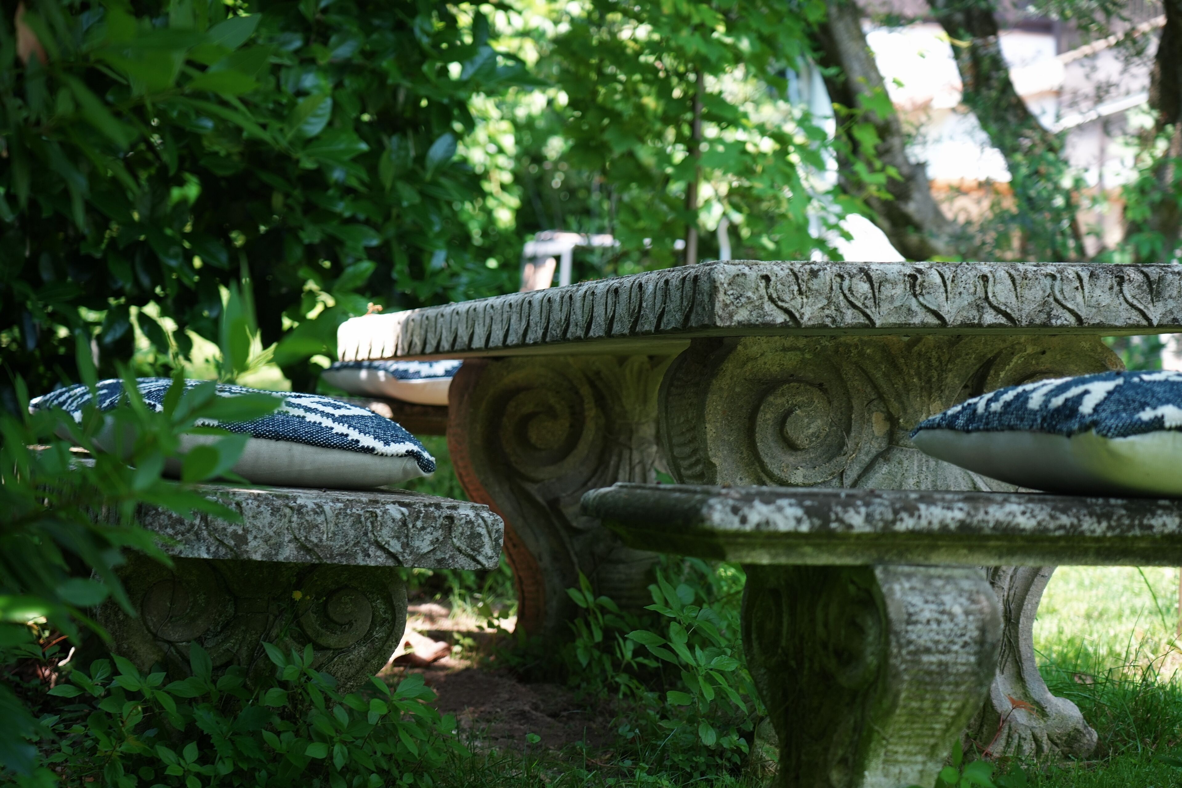 Un banc en pierre orné de motifs sculptés et doté d’un coussin.