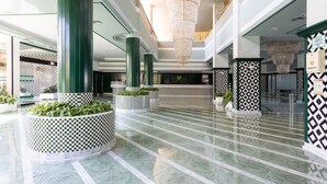 A spacious lobby with high ceilings, large columns, and a checkered floor pattern.