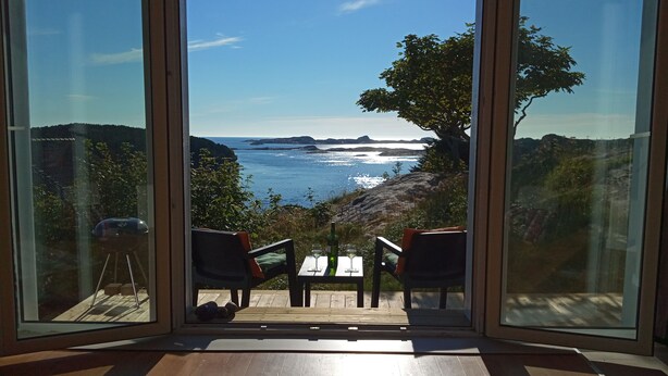 Una habitación con paredes de vidrio que ofrece vistas al mar y a las colinas.
