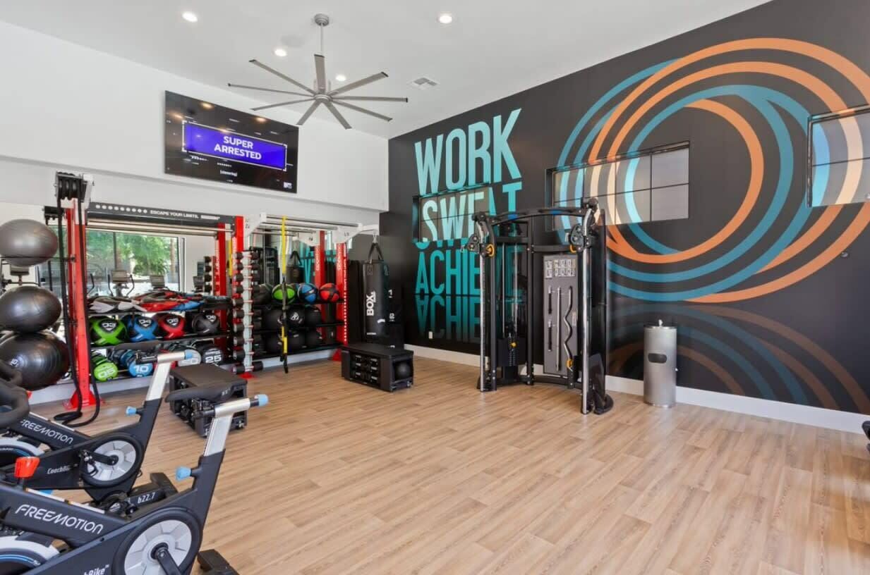 A gym with exercise equipment, a motivational wall, and a TV screen displaying 'SUPER ARRESTED'.