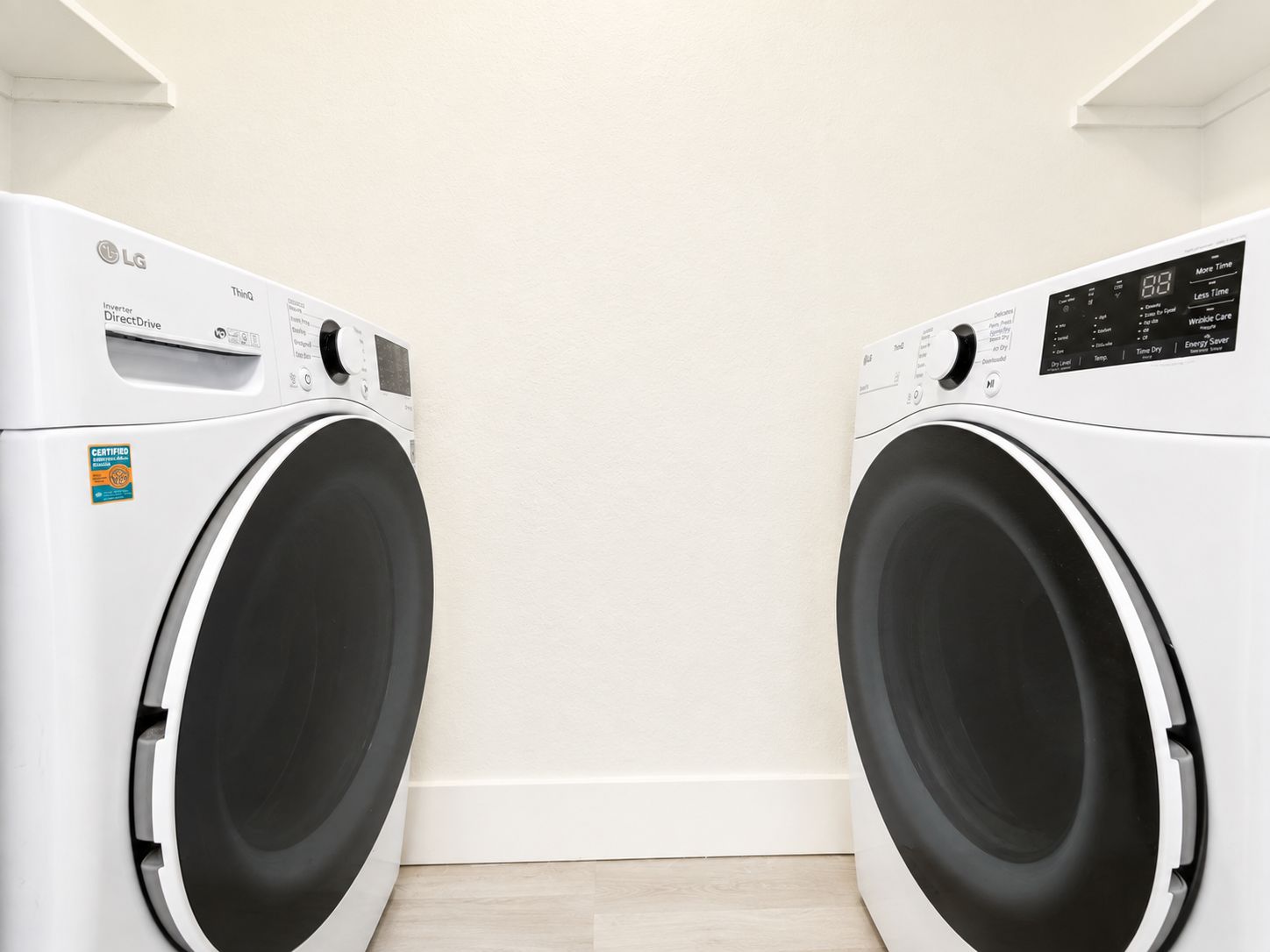 Twee LG Inverter DirectDrive voorladers in een wasserij met een effen witte muur en houten vloer.