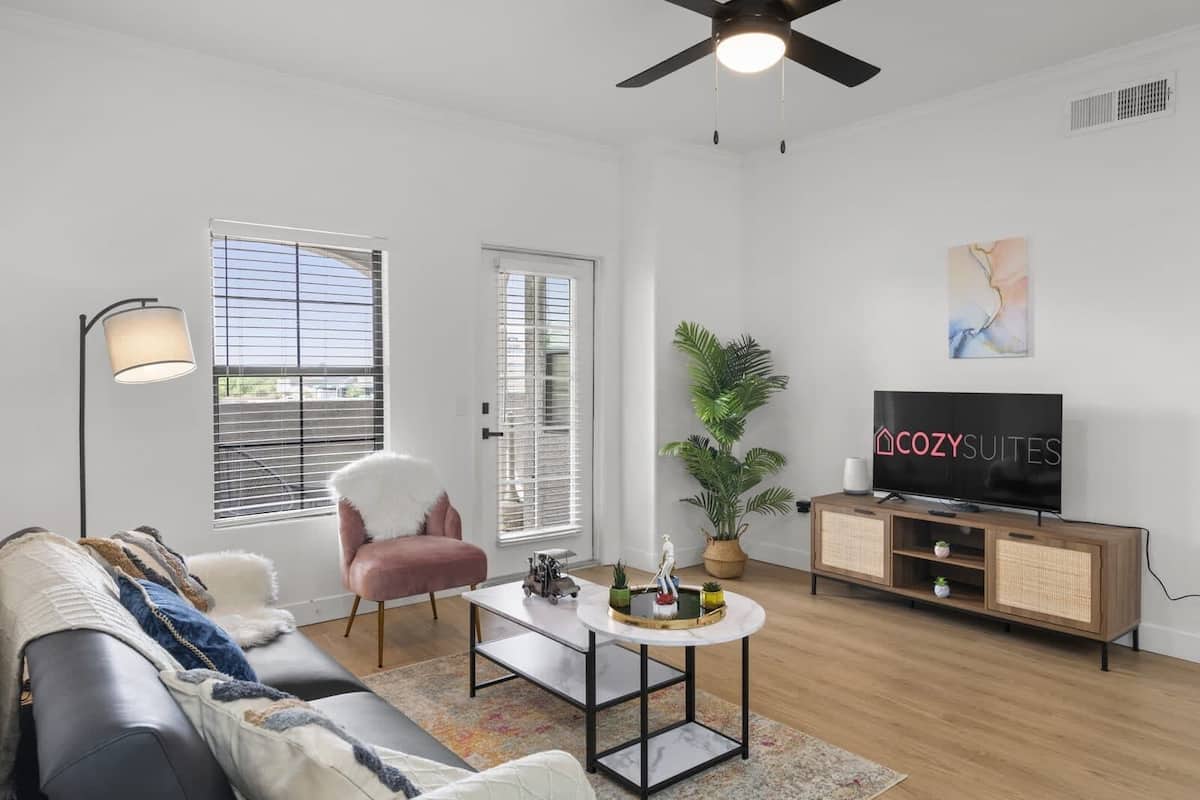 A modern living room with a sofa, a coffee table, a TV, and a ceiling fan.