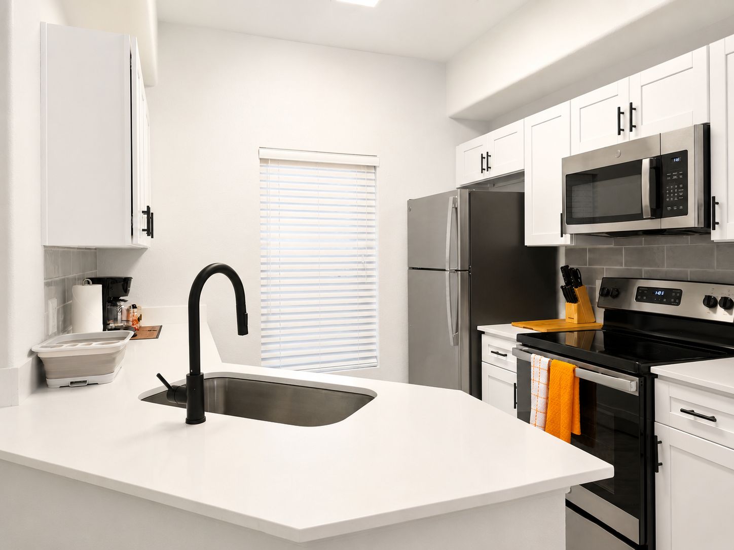 A modern kitchen with a central island, stainless steel appliances, and white cabinetry.