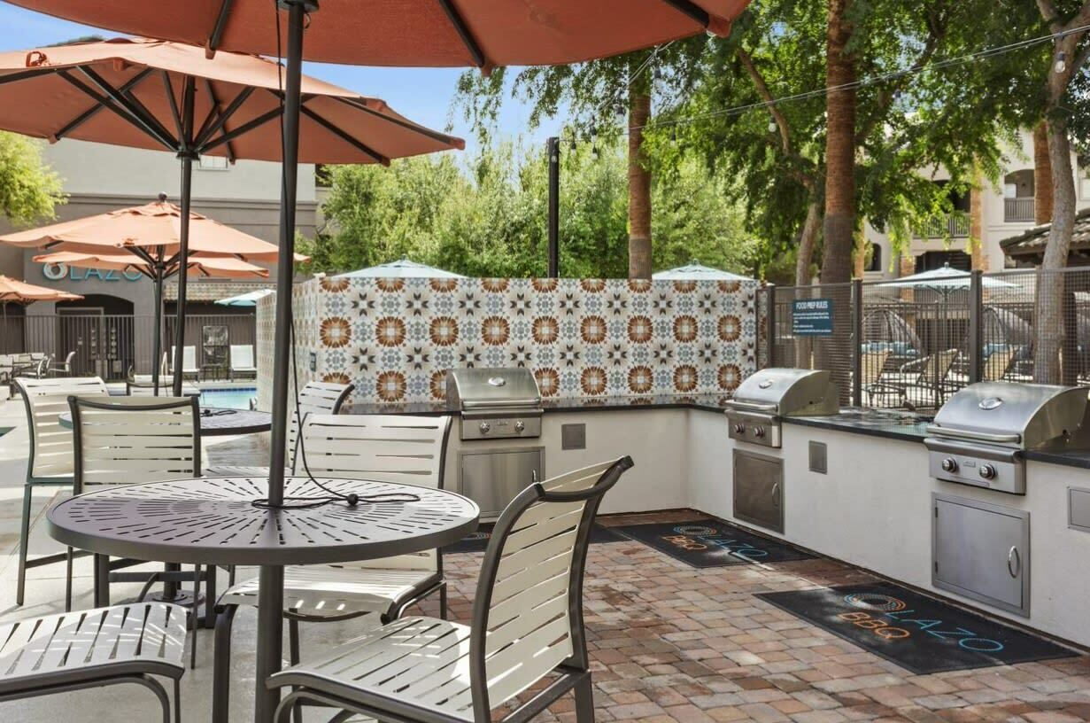 Eine Terrasse im Freien mit Grill, Sitzgelegenheit und Poolbereich.
