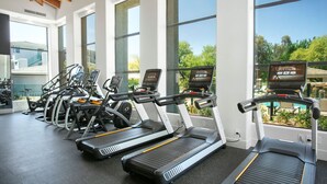 A gym with multiple treadmills, large windows, and a view of the outdoors. - CozySuites at Kierland Commons (Scottsdale)