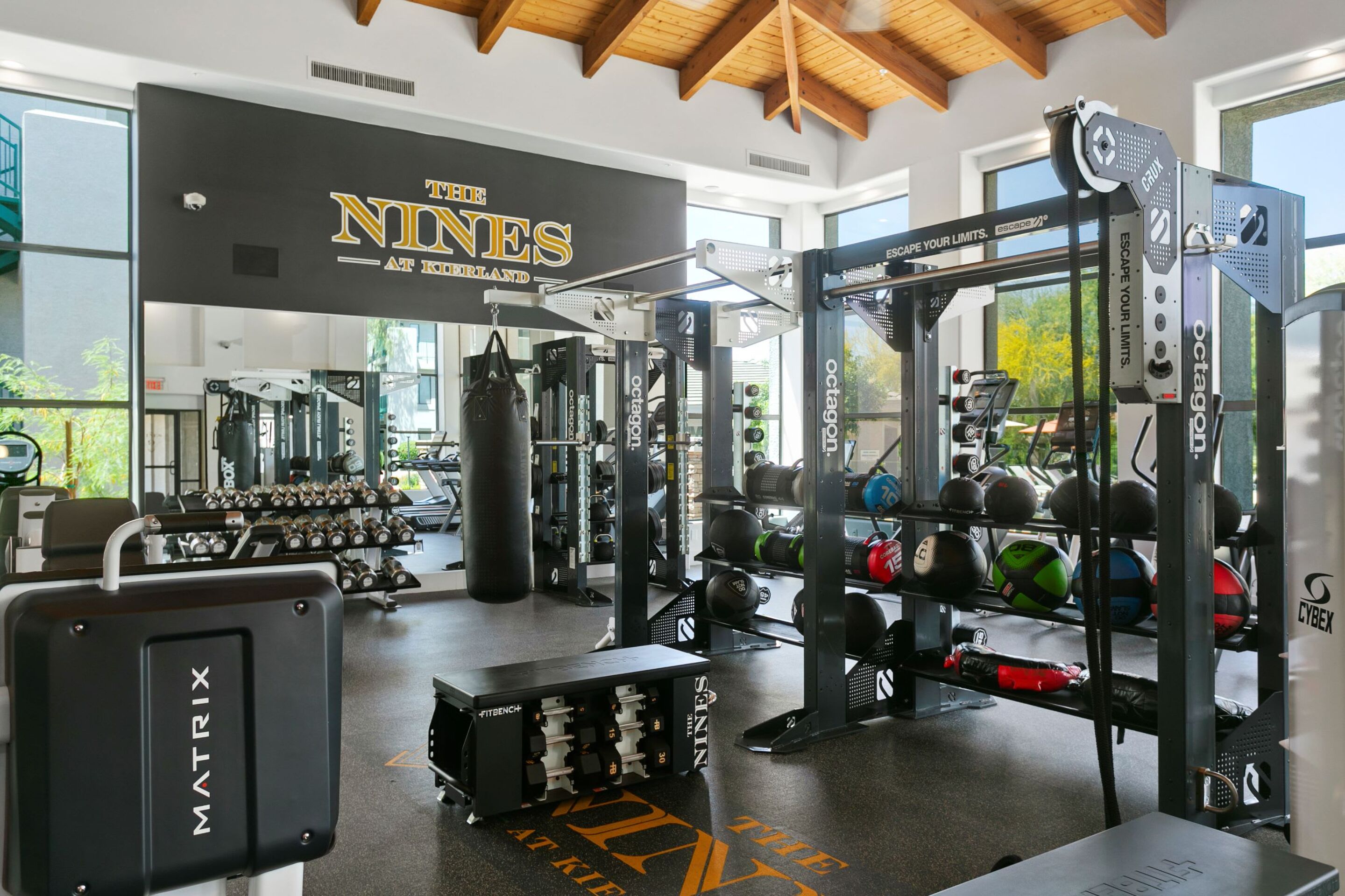 Ein Fitnessraum mit Gewichthebern, einem Boxsack und einem Schild mit der Aufschrift 'The Nines at Kirtland'.