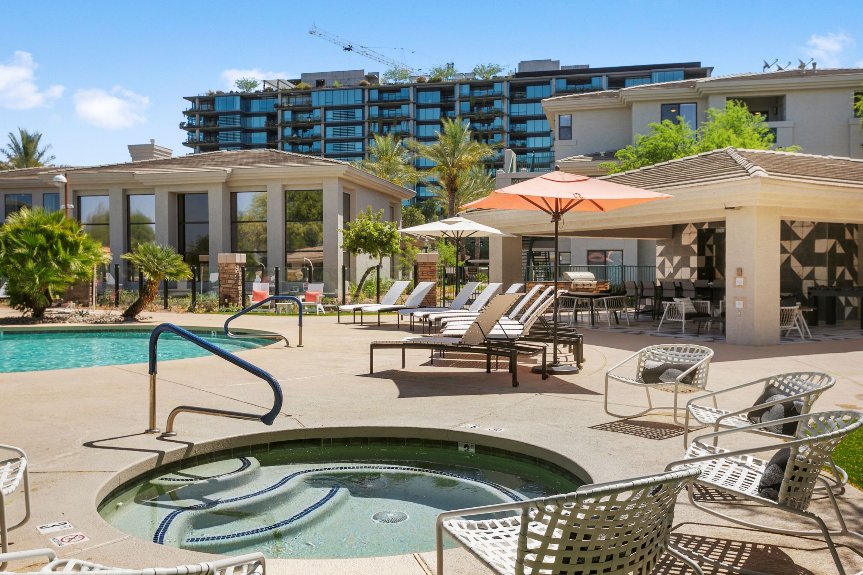 Ein Hotelpool mit Liegestühlen, einem Whirlpool und einer überdachten Sitzgelegenheit.