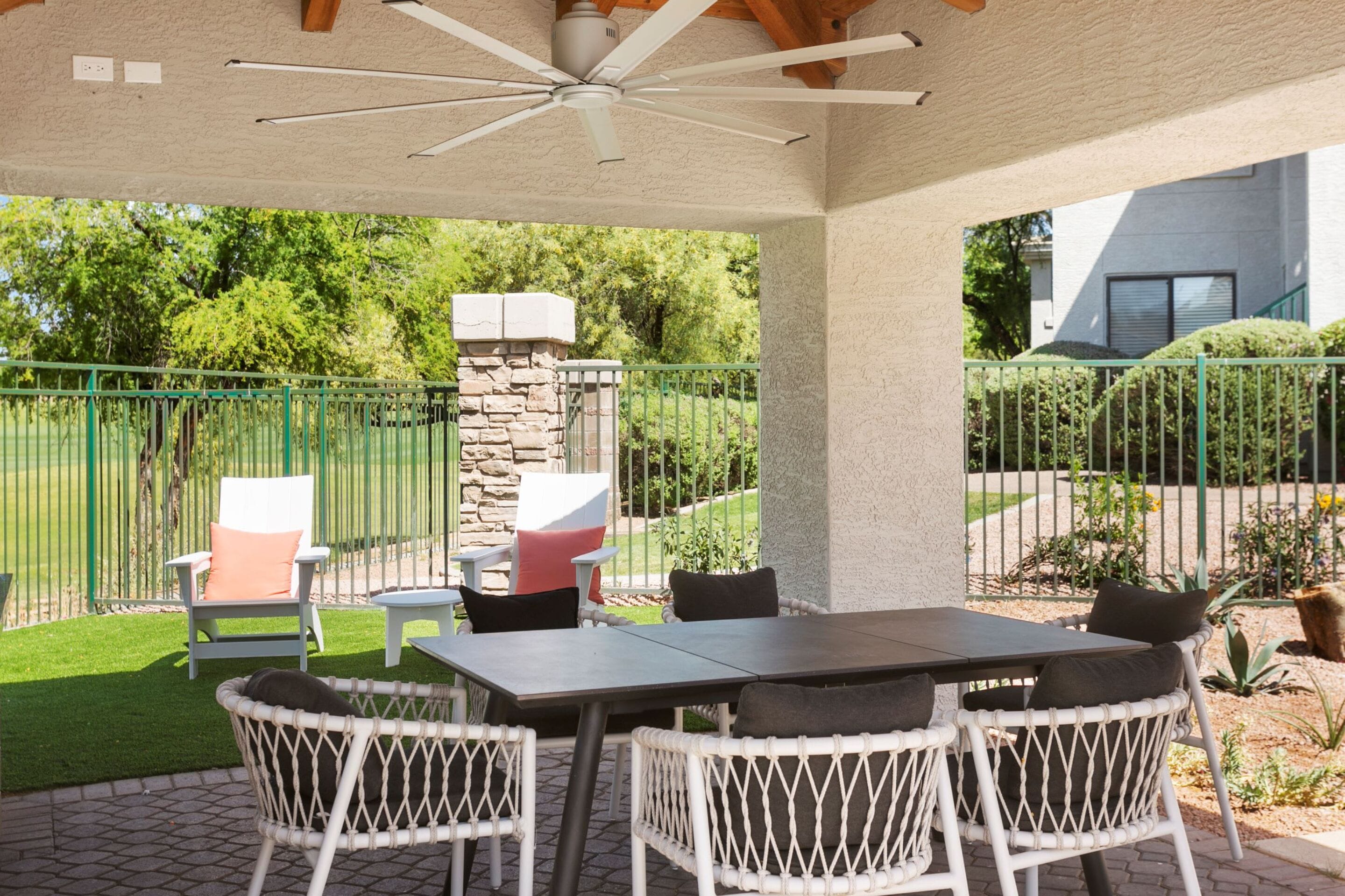 Un espace extérieur aménagé en terrasse, avec une cheminée en pierre, des chaises en osier blanc et une table.