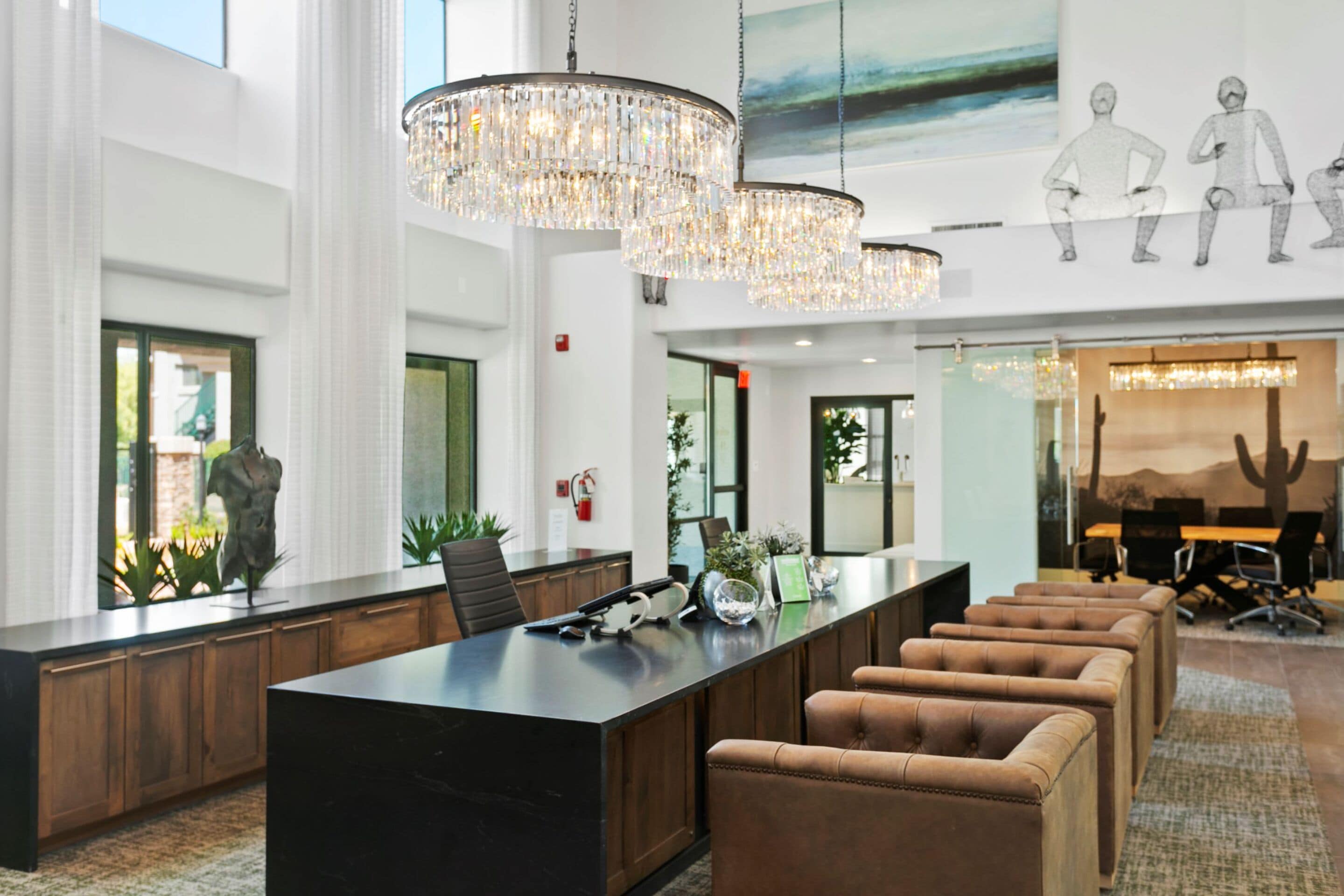 A modern reception area with a marble counter, leather seating, and a large chandelier.