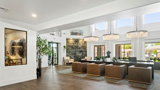 A spacious living area with a large dining table, multiple sofas, and a stone accent wall. - CozySuites at Kierland Commons (Scottsdale)