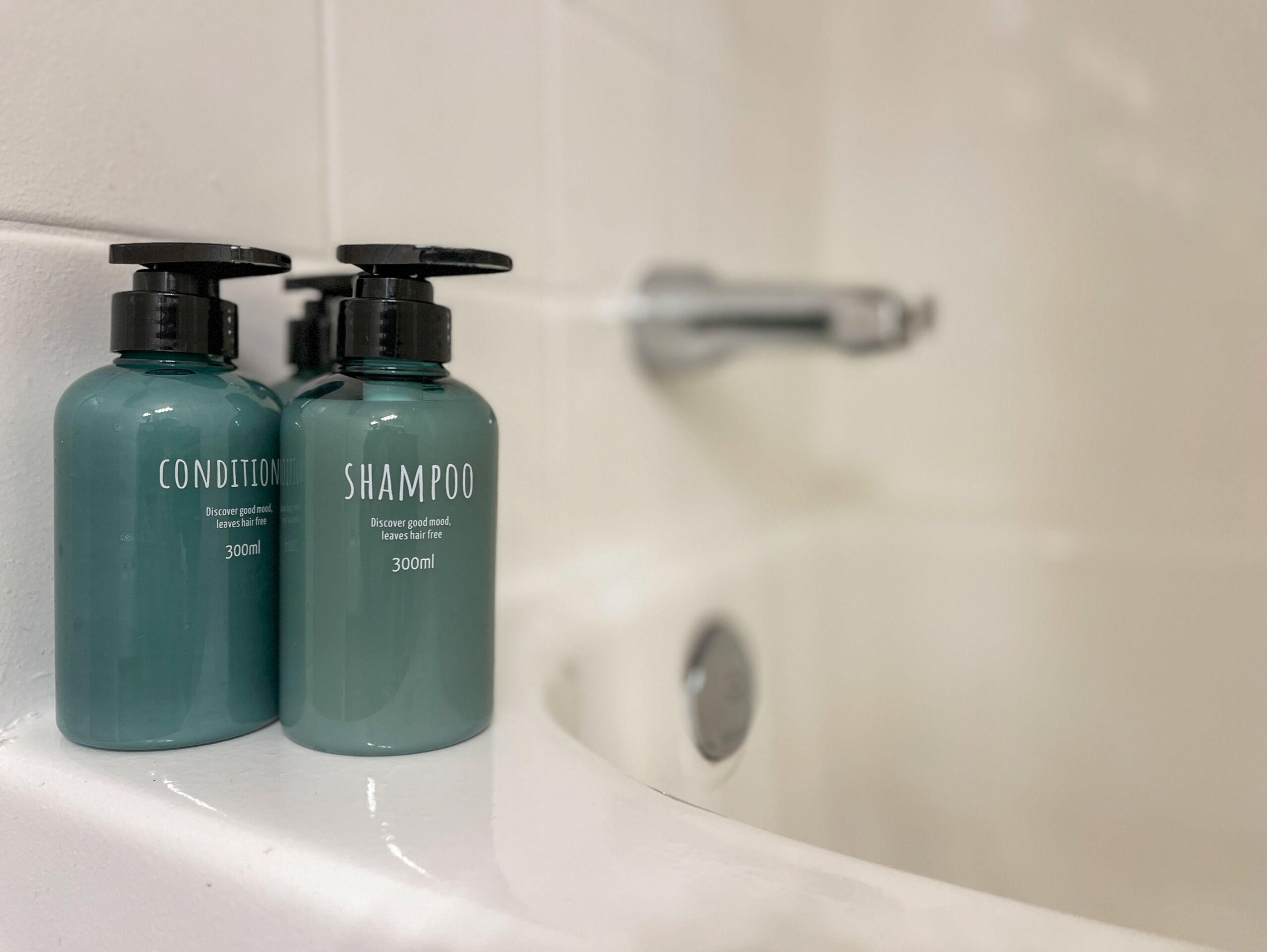 Two bottles of shampoo and conditioner on a white bathtub.