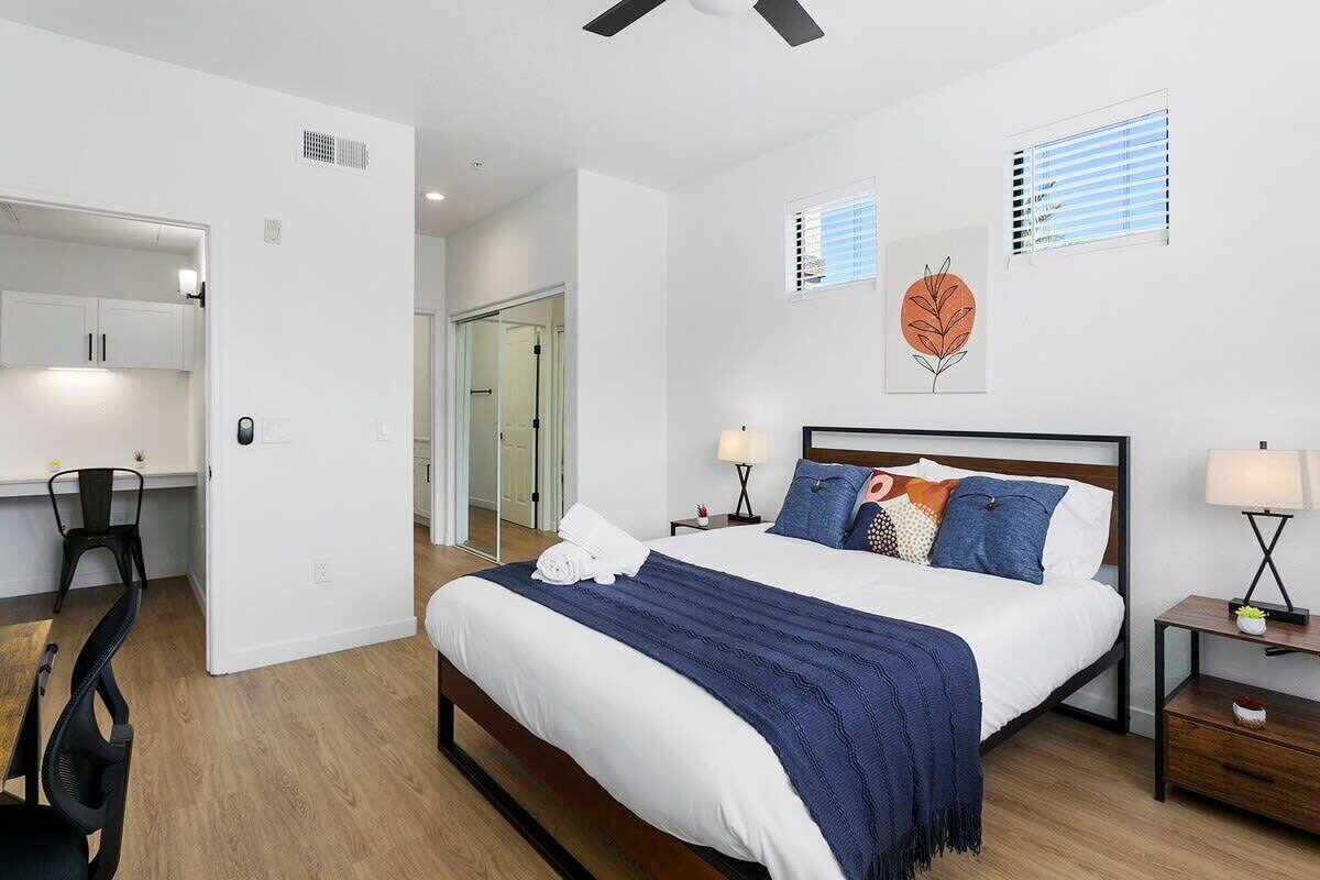 A bedroom with a bed, bedside tables, a desk, and a chair.
