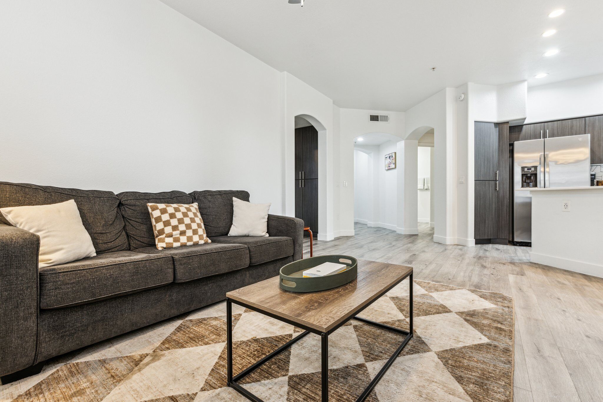 A modern living room with a grey sofa, a coffee table, and a patterned rug.