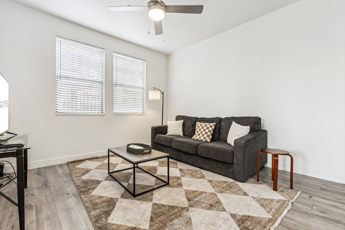 A modern living room with a grey sofa, a small table, and a checkered rug.