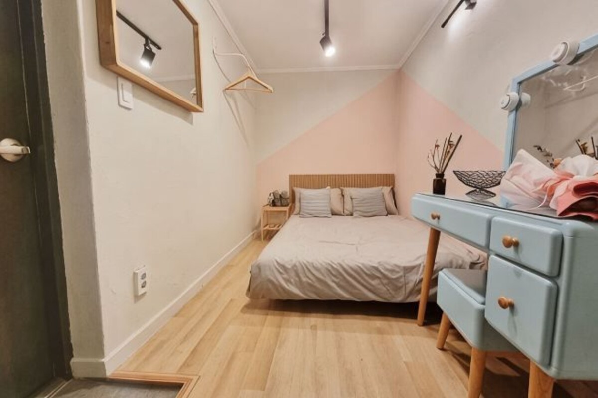A bedroom with a bed, bedside table, dresser, and a mirror.