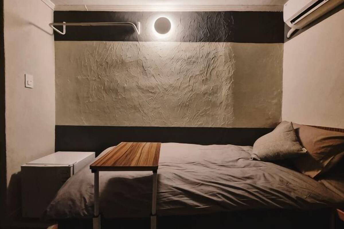 Un dormitorio con cama, mesita de noche y lámpara de pared.