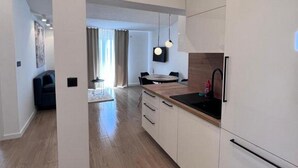 A modern kitchen with white cabinets, a wooden countertop, and a black sink.