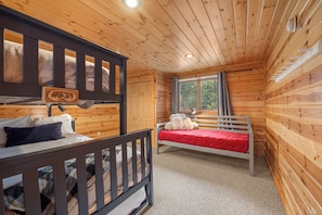A cabin with two bunk beds, a window with curtains, and a wooden ceiling. - Maine Lodge with Fireplace and Pool Table (Bethel)