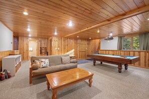 A cozy room with a pool table, a sofa, and a wooden ceiling. - Maine Lodge with Fireplace and Pool Table (Bethel)
