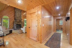 A wooden interior with a stone fireplace, a door, and a view of the outdoors. - Maine Lodge with Fireplace and Pool Table (Bethel)
