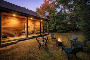 A log cabin with a porch, outdoor seating, and a fire pit. - Maine Lodge with Fireplace and Pool Table (Bethel)
