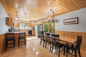 A spacious kitchen with wooden cabinets, a large island with bar stools, and a dining table with chairs.