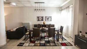 Ein moderner Essbereich mit einer schwarzen Couch, einem Esstisch mit sechs Stühlen, einer Heizung und einem farbenfrohen Teppich.