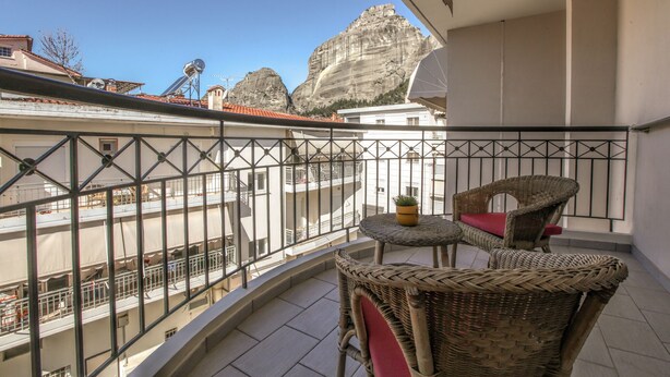 Ein Balkon mit Korbmöbeln, einem Blumentopf und Blick auf einen Berg.