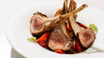 A plate of cooked lamb chops with vegetables.
